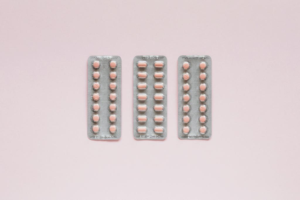3 packs of pale pink pills in silver pill packs on light pink surface