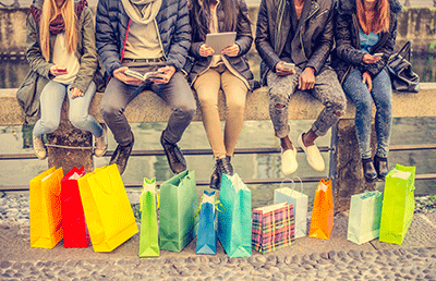 Individuals sitting on ledge with shopping bags
