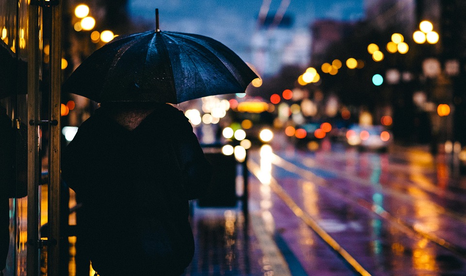 Adult standing in rain with umbrella