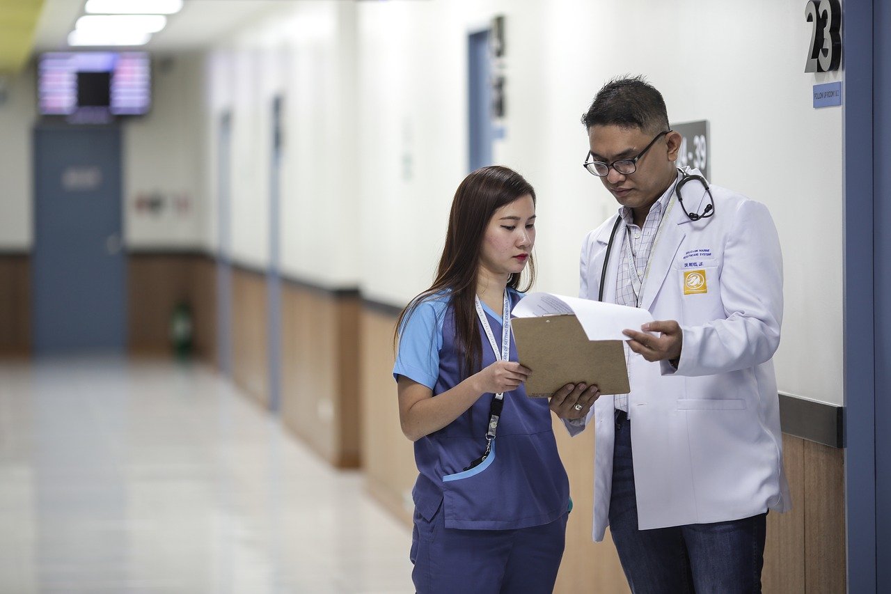 Nurse and doctor standing in hallway looking at clipboard