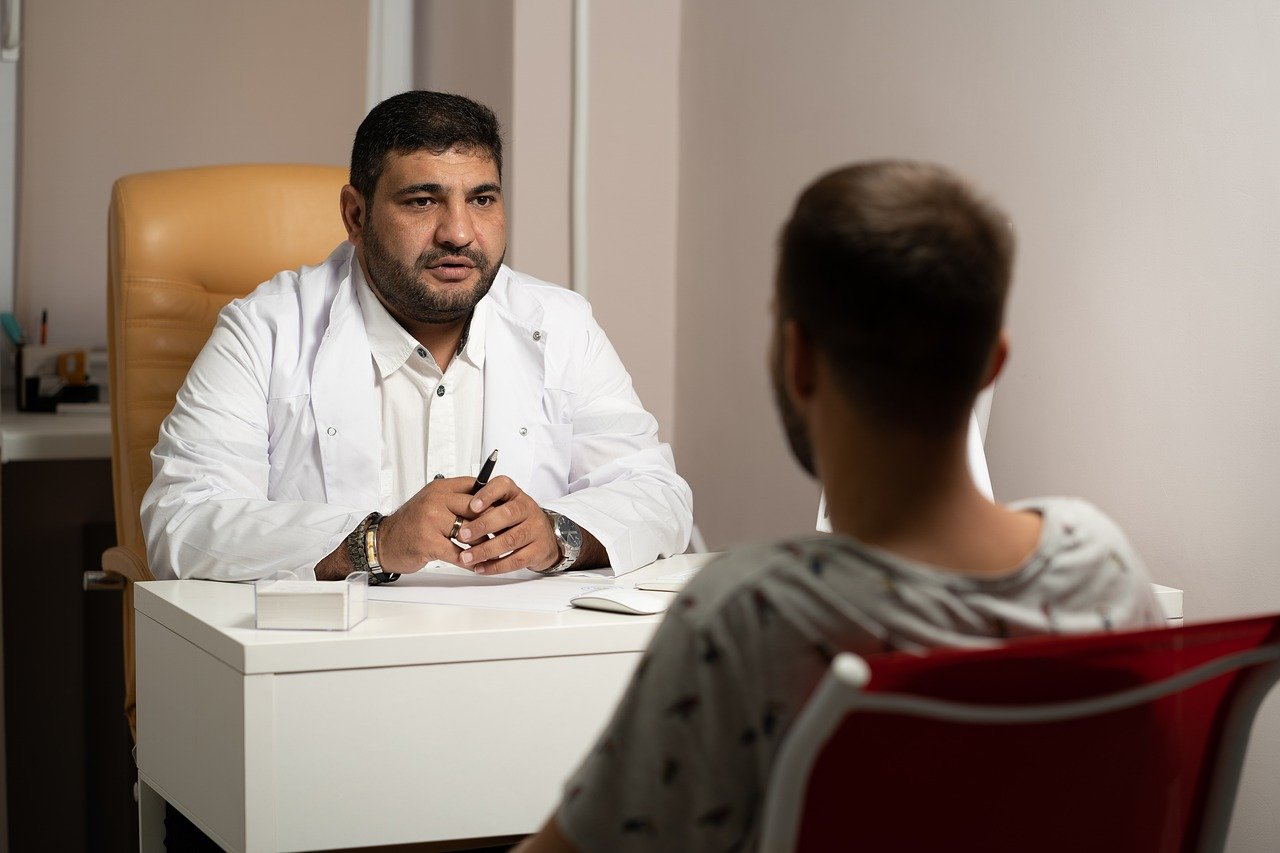 Doctor sitting at desk speaking with patient Image by Sozavisimost from Pixabay 