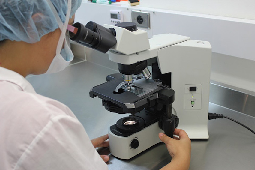 Technician using microscope