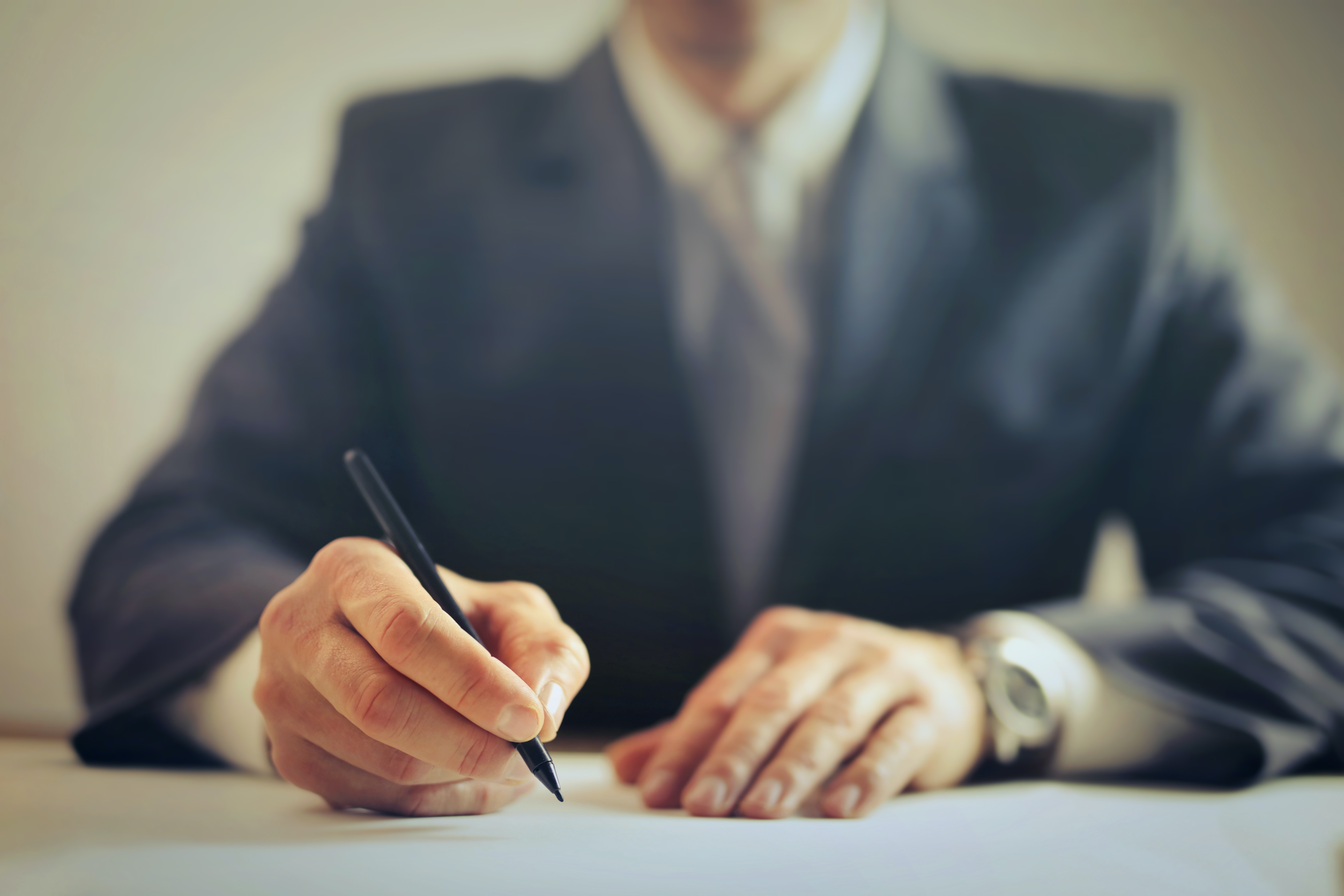 Man in suit writing on paper Photo by Andrea Piacquadio from Pexels