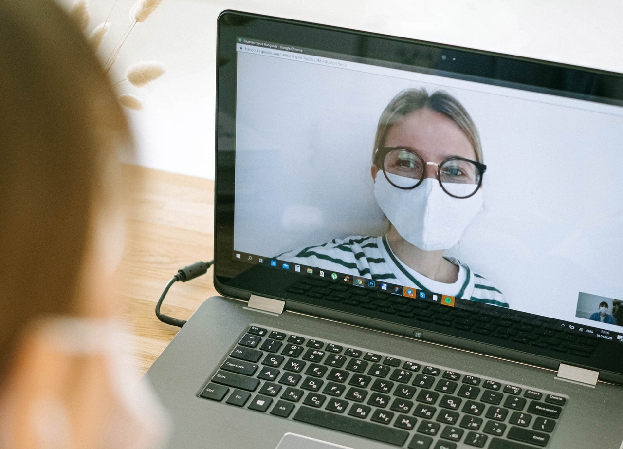 woman on video chat wearing surgical mask Photo by Ivan Samkov from Pexels