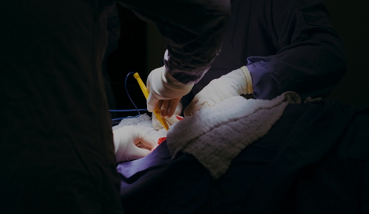 group of surgeons operating on lit patient in dark room