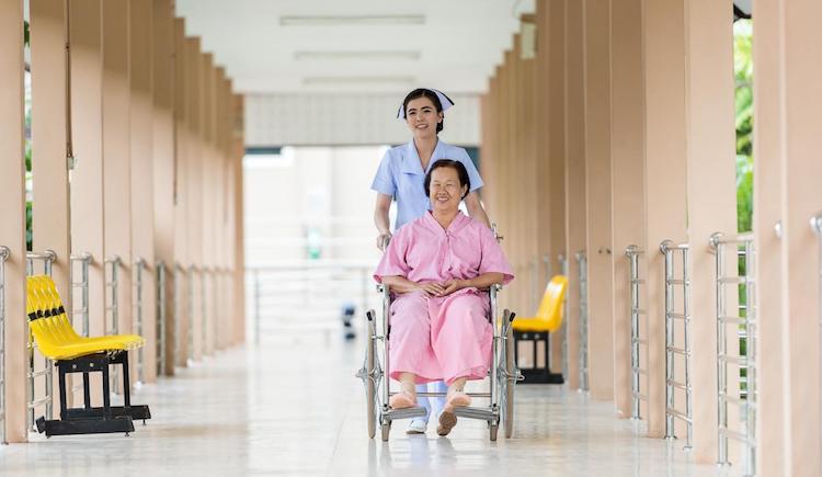 Nurse pushes patient in wheelchair