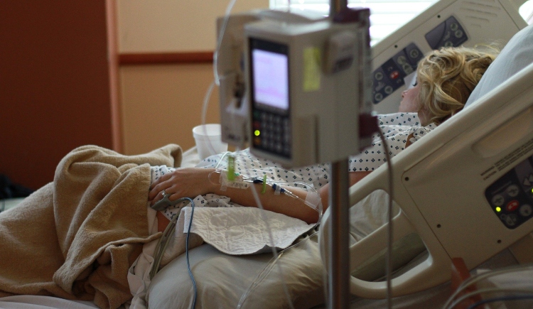 Person laying in hospital bed with monitor in foreground