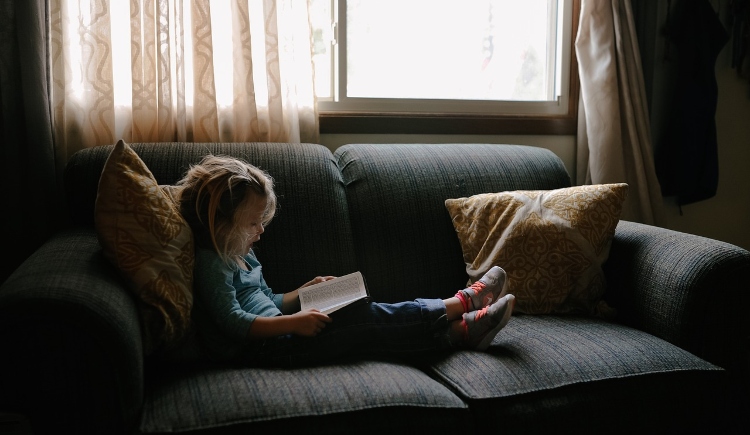 Child sitting on couch reading a book