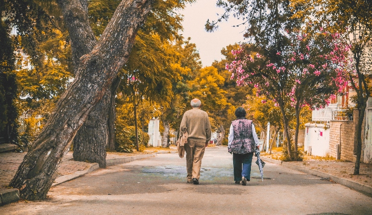 Elderly man & woman walking down tree-lined street. Photo by Emre Kuzu from Pexels