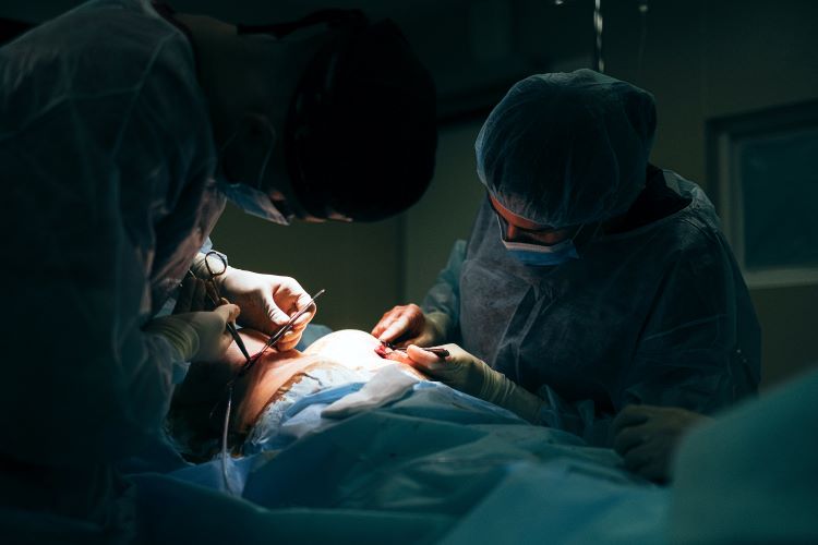 surgeons at work in dark room with light on patient
