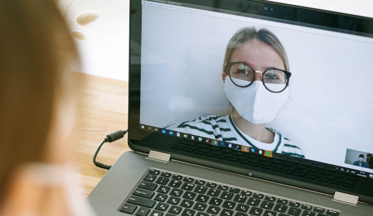 woman on video chat wearing surgical mask Photo by Ivan Samkov from Pexels
