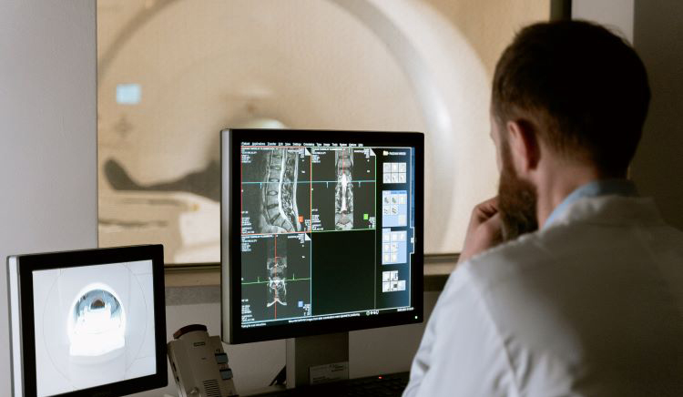 man looks at computer images generated by MRI scan