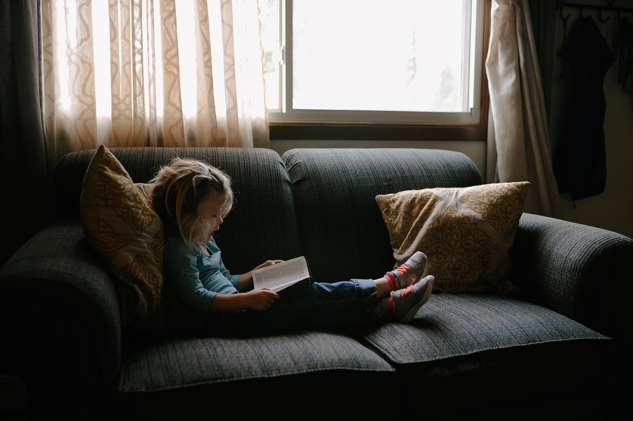 Child sitting on couch reading a book